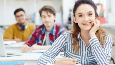 Happy young girl listening to teacher at lesson